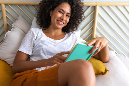 Young woman enjoying weekend reading in bed