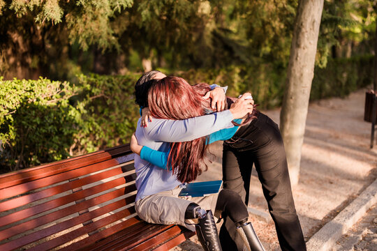 Man with prosthetic legs hugging female friend in park