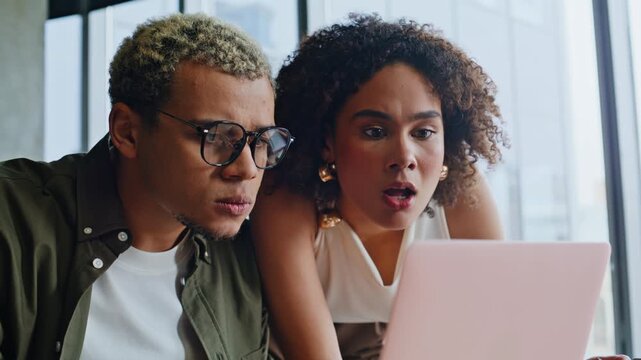 Frustrated business partners reacting to bad news on laptop in office meeting