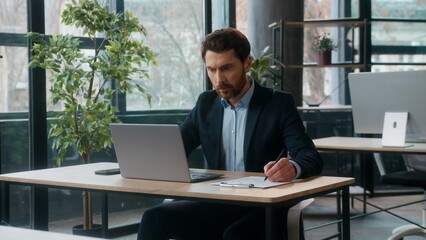 Fototapeta premium Confident Caucasian businessman writing tasks notes working on laptop in office successful professional adult male business man guy manager accountant employer leader accounting work typing computer