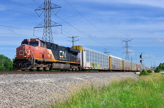 A single Canadian National Railway locomotive leads an auto rack train southbound as it passes through northeastern Illinois.