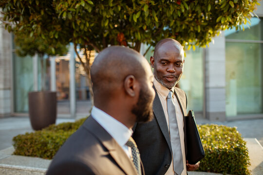 Two businessmen talking while walking outside office