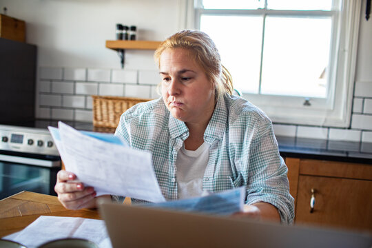 Concerned woman reviewing household bills at kitchen table