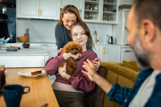 Happy family bonding with puppy in kitchen