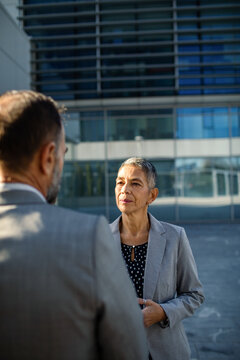 Senior businesswoman talking with colleague outside office