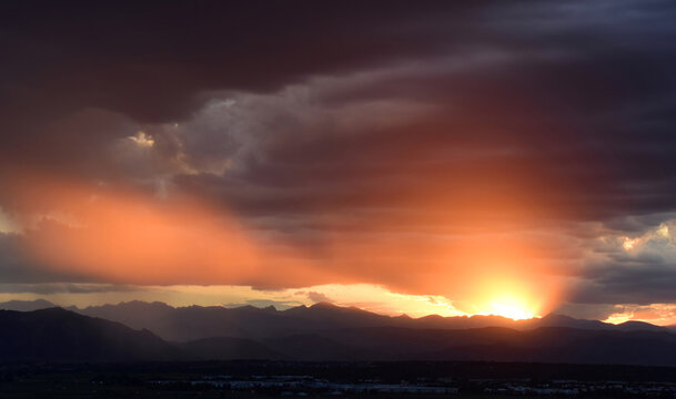 colorful, dramatic sunset and dark clouds over boulder's flatirons and the front range of the colorado rocky mountains, as seen from broomfield, colorado