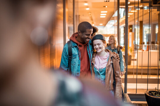 Young friends laughing while walking through modern building lobby