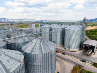 Large industrial silos located on a farm in a rural area surrounded by fields and hills under a partly cloudy sky during the day © DSMT
