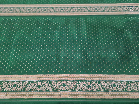 Green Islamic prayer carpet texture pattern inside mosque floor	