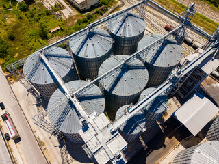 Large grain silos at a storage facility with a road and rail tracks nearby during daytime © DSMT