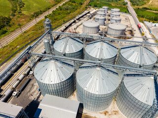 Large storage silos located near a railway track in a rural area during the daytime with trucks near the facility © DSMT