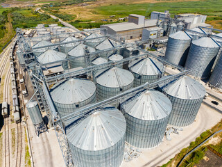 Grain storage facility located near a railway, showing large silos and industrial structures during daylight © DSMT