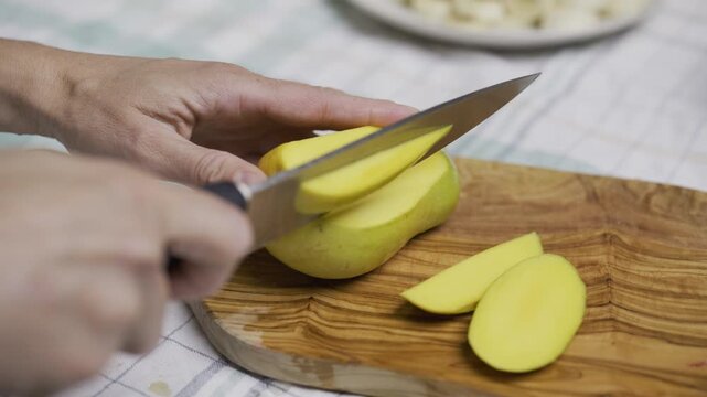 Closeup of person cutting up mango into squares