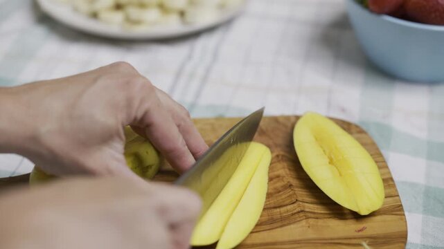 Chef cutting up Mango slice into squares on cutting board, closeup