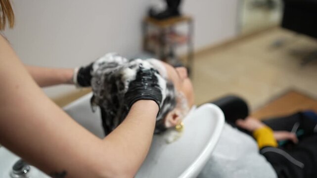 Hairdresser massaging and washing customer's hair