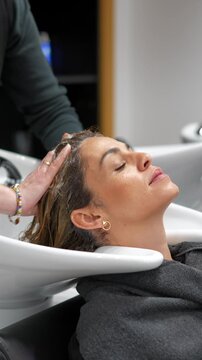 Relaxed woman receiving a hair wash and scalp massage at a beauty salon