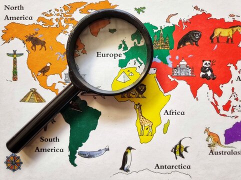 Magnifying glass zooming in on Europe on a colorful illustrated world map with global landmarks.