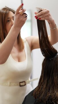 Professional hairdresser cutting woman's hair with scissors