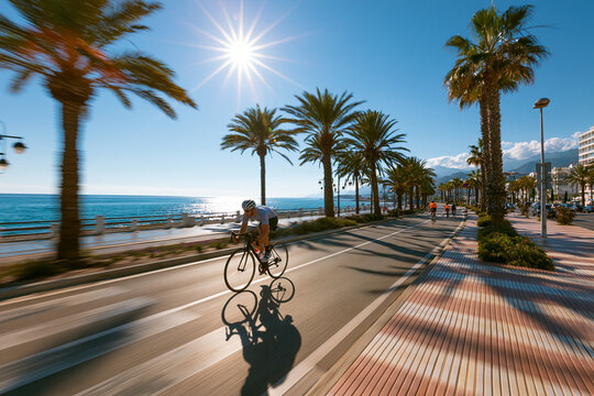 Cyclist speeding along a sunny coastal boulevard