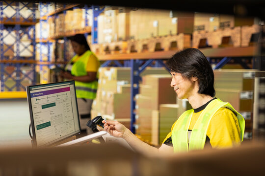 Logistics worker monitors shipment details on a package tracking interface, updating delivery routes and parcel data with air waybill numbers in the stock room.