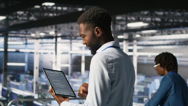 Data center programmers on industrial platform checking lines of code, collaborating on tasks, with server hub IT specialists visualizing large language model architecture using tablet and PC.