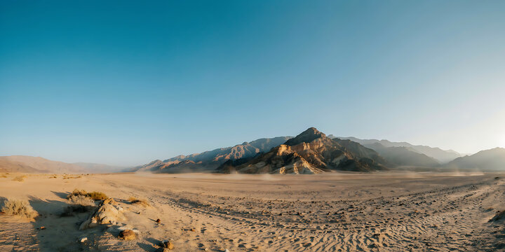 A wide panoramic shot of a dry desert valley with sandy dunes and distant rocky mountains under a clear blue sky in the bright afternoon sun