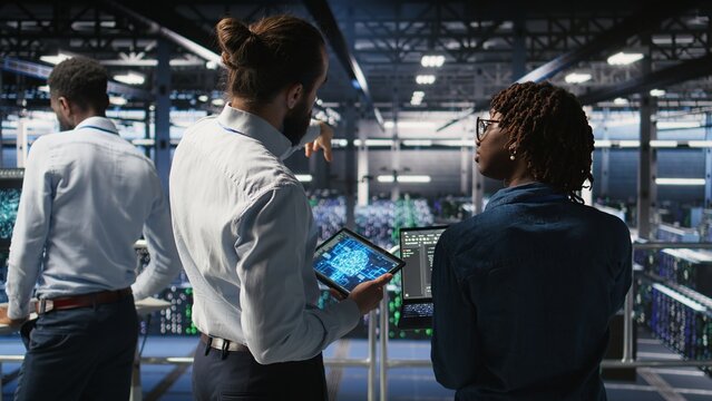 A server farm manager oversees workers automating AI infrastructure; a team leader supervises employees using artificial intelligence to support reliable operations and machine learning systems.