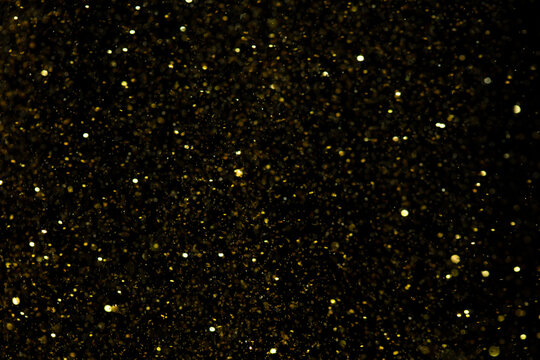 Photo of golden glitter powder sand creating abstract bokeh festive atmosphere. Bokeh of particle element of gold glitter sand light up luxury  background, sparkle glow wallpaper