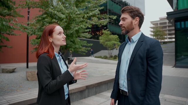 Caucasian business male female managers in city discussing project deal together two people partners meet outdoor discuss colleagues coworkers businessman businesswoman man woman talking collaborative