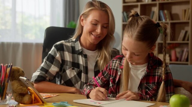 Caucasian daughter little girl writing homework woman mother help study together happy family kid student write in copybook schoolgirl pupil school exercise mom teach female tutor at home parent child