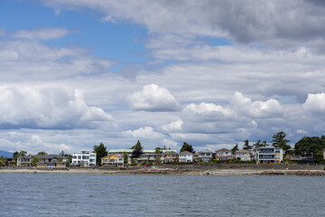 Naklejka premium Waterfront Homes Along Sidney Shoreline Under Dramatic Cloudy Sky on Vancouver Island, BC, Canada