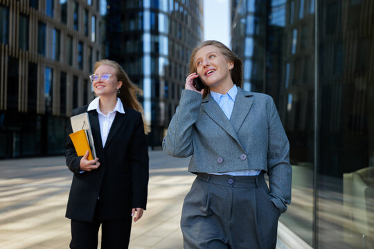 Businesswomen enjoying a sunny day while walking and talking in a modern cityscape