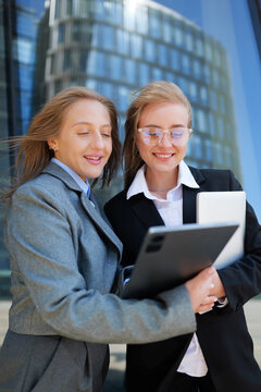 Two professional women discussing ideas while standing outdoors near a modern office building