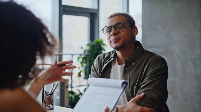 Cheerful man discussing documents recruiter woman. Job interview office meeting.