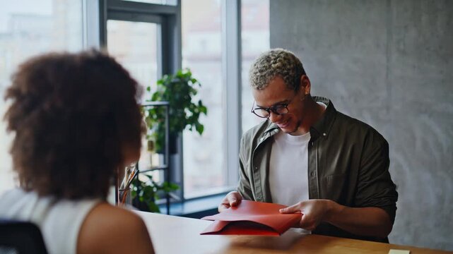 Business partners exchanging red folder, handshake closing deal, handheld office