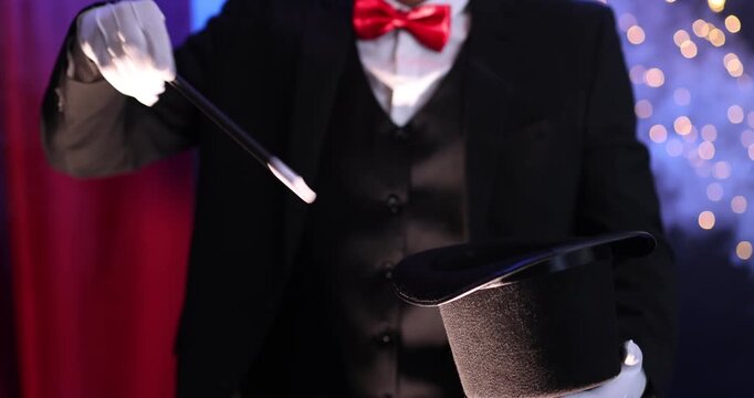 Magician showing trick with wand and top hat on stage with smoke, closeup