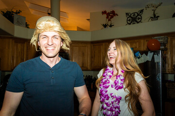 Smiling friends in modern kitchen wearing colorful leis during casual celebration © Allison