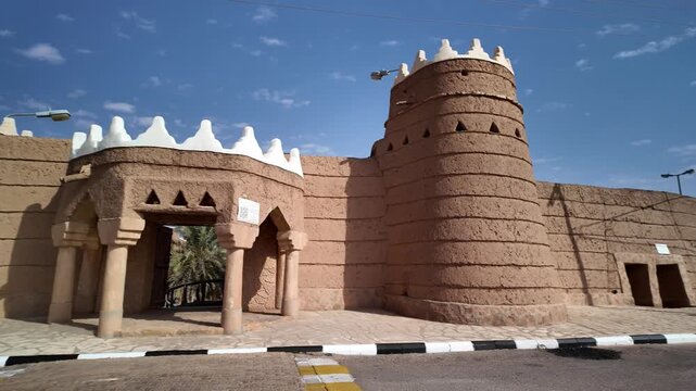 Ushaiqer Heritage Village mud-brick walls and arched entrance showcasing Najdi adobe architecture under a clear blue sky, historic desert village preserved for tourism and culture of Saudi Arabia