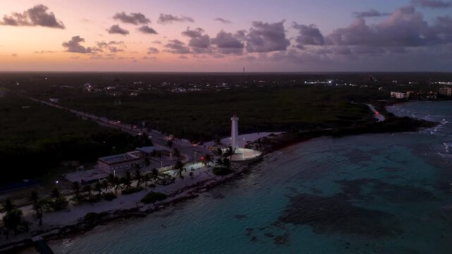 Panoramic aerial view of illuminated Mahahual lighthouse and coastline at sunset in Mexico