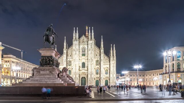 Night view of Milan Cathedral illuminated against the evening sky with the equestrian statue of Victor Emmanuel II in Piazza del Duomo, Italy.