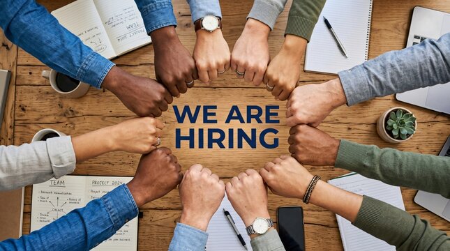 We Are Hiring recruitment concept, diverse business team fist bump in circle over wooden table, corporate human resources and talent acquisition