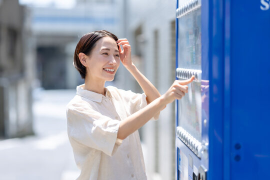 自動販売機で飲み物を買う女性