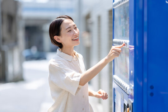 自動販売機で飲み物を買う女性