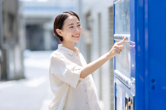 自動販売機で飲み物を買う女性