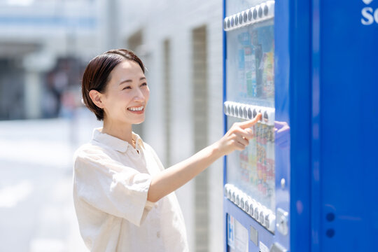 自動販売機で飲み物を買う女性
