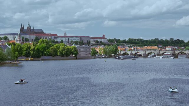 Panoramic view of historic Prague skyline, featuring Prague Castle complex, Charles Bridge arches, and Vltava River on a cloudy day