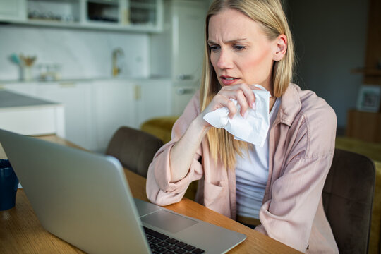 Young woman with cold working on laptop at home