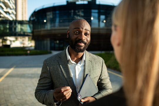 Business professional discussing with a colleague outside an office building
