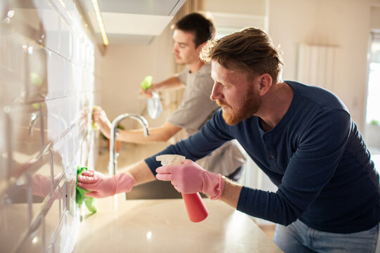 Two men cleaning kitchen at home