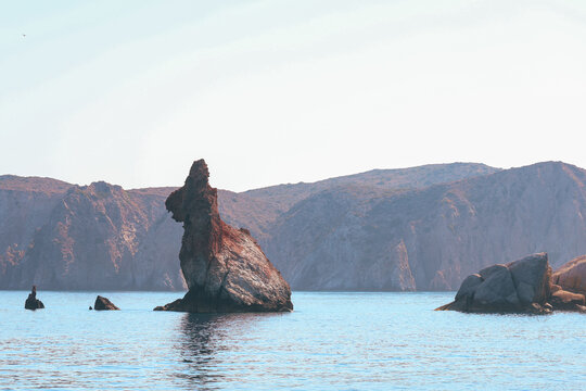 The famous Rabbit Rock (Petra Lagou) off the coast of Milos, Greece, resembles a rabbit rising from the sea against rugged volcanic cliffs.